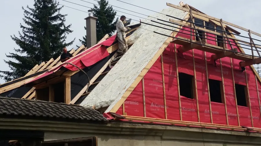 Sedlová střecha při rekonstrukci s nastříkanou pěnou na štítu a červenou pojistnou fólií